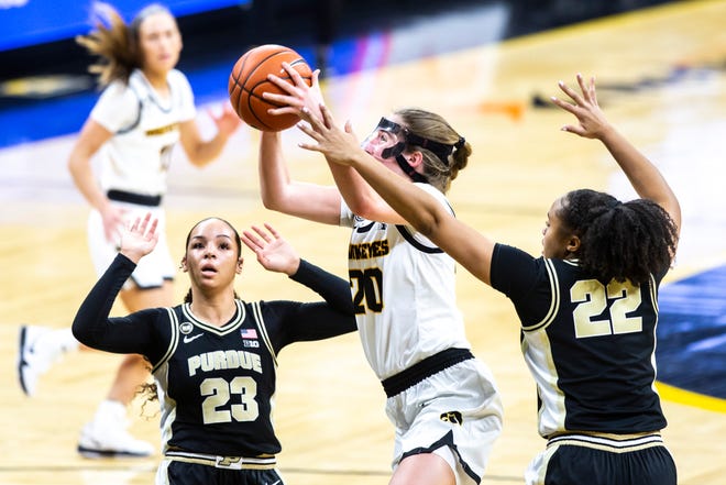 Iowa guard Kate Martin (20) makes a basket as Purdue guard Kayana Traylor (23) and Purdue's Jelle Grant (22) defend during a NCAA Big Ten Conference women's basketball game, Monday, Jan. 18, 2021, at Carver-Hawkeye Arena in Iowa City, Iowa.