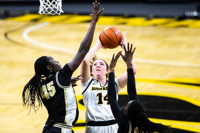Iowa's McKenna Warnock (14) makes a basket as Purdue center Fatou Diagne (45) and Purdue's Tamara Farquhar, right, defend during a NCAA Big Ten Conference women's basketball game, Monday, Jan. 18, 2021, at Carver-Hawkeye Arena in Iowa City, Iowa.