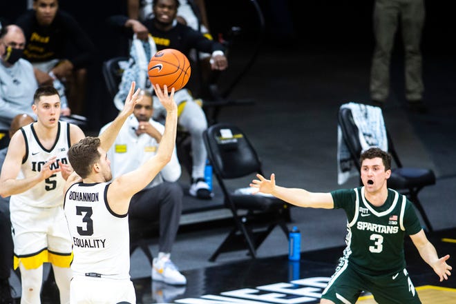 Iowa guard Jordan Bohannon, left, makes a 3-point basket during a NCAA Big Ten Conference men's basketball game against Michigan State, Tuesday, Feb. 2, 2021, at Carver-Hawkeye Arena in Iowa City, Iowa.