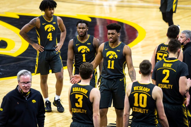 Iowa guard Tony Perkins (11) reacts returning to the huddle with teammates Joe Toussaint (1) and Ahron Ulis (4) during a NCAA Big Ten Conference men's basketball game, Thursday, Feb. 4, 2021, at Carver-Hawkeye Arena in Iowa City, Iowa.