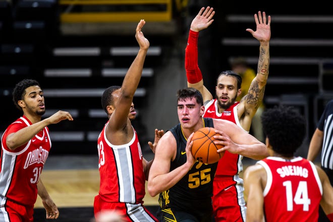 Iowa center Luka Garza (55) passes the ball as Ohio State forwards Seth Towns (31) and Zed Key (23) and guard Duane Washington Jr., right, defend during a NCAA Big Ten Conference men's basketball game, Thursday, Feb. 4, 2021, at Carver-Hawkeye Arena in Iowa City, Iowa.