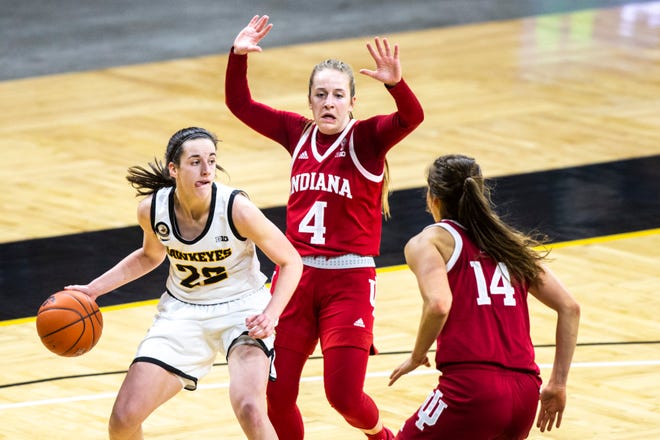 Iowa guard Caitlin Clark, left, dribbles as Indiana guard Nicole Cardaño-Hillary (4) and Indiana guard Ali Patberg (14) defend during a NCAA Big Ten Conference women's basketball game, Sunday, Feb. 7, 2021, at Carver-Hawkeye Arena in Iowa City, Iowa.
