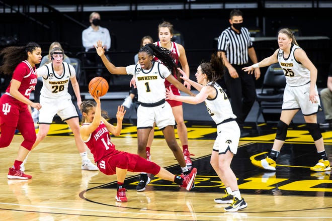 Indiana guard Ali Patberg (14) slips as Iowa guard Tomi Taiwo (1) and Iowa guard Caitlin Clark, second from right, defend during a NCAA Big Ten Conference women's basketball game, Sunday, Feb. 7, 2021, at Carver-Hawkeye Arena in Iowa City, Iowa.
