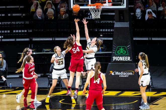 Indiana forward Mackenzie Holmes (54) makes a basket as Iowa forward Logan Cook (23) and Iowa's McKenna Warnock, center right, defend during a NCAA Big Ten Conference women's basketball game, Sunday, Feb. 7, 2021, at Carver-Hawkeye Arena in Iowa City, Iowa.
