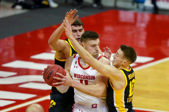 Iowa's Luka Garza, left, and Iowa's Joe Wieskamp (10) surround Wisconsin's Micah Potter (11) during the first half of an NCAA college basketball game Thursday, Feb. 18, 2021, in Madison, Wis. (AP Photo/Andy Manis)