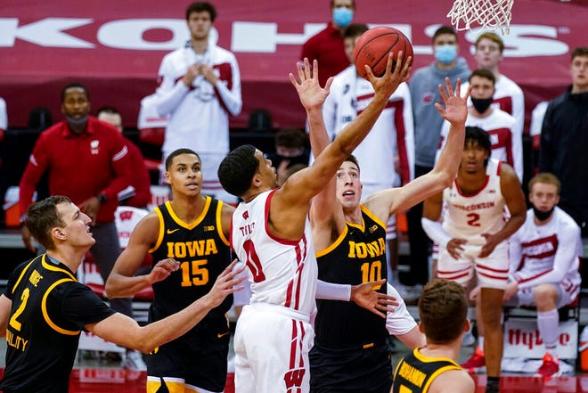Wisconsin's D'Mitrik Trice (0) goes up against Iowa's Jack Nunge (2) and Joe Wieskamp (10) during the second half of an NCAA college basketball game Thursday, Feb. 18, 2021, in Madison, Wis. (AP Photo/Andy Manis)