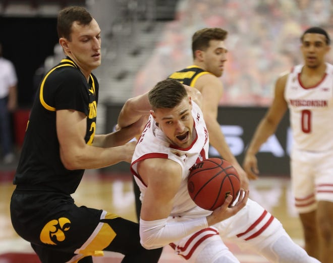 Feb 18, 2021; Madison, Wisconsin, USA; Wisconsin Badgers forward Micah Potter (11) works to control the ball as Iowa Hawkeyes forward Jack Nunge (2) defends during the first half at the Kohl Center. Mandatory Credit: Mary Langenfeld-USA TODAY Sports