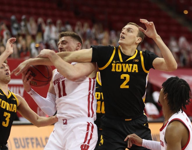 Feb 18, 2021; Madison, Wisconsin, USA; Wisconsin Badgers forward Micah Potter (11) works to control the ball as Iowa Hawkeyes forward Jack Nunge (2) defends during the first half at the Kohl Center. Mandatory Credit: Mary Langenfeld-USA TODAY Sports