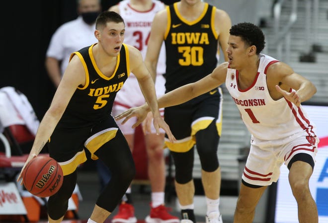 Feb 18, 2021; Madison, Wisconsin, USA; Iowa Hawkeyes guard C.J. Fredrick (5) dribbles the ball as Wisconsin Badgers guard Jonathan Davis (1) defends during the first half at the Kohl Center. Mandatory Credit: Mary Langenfeld-USA TODAY Sports