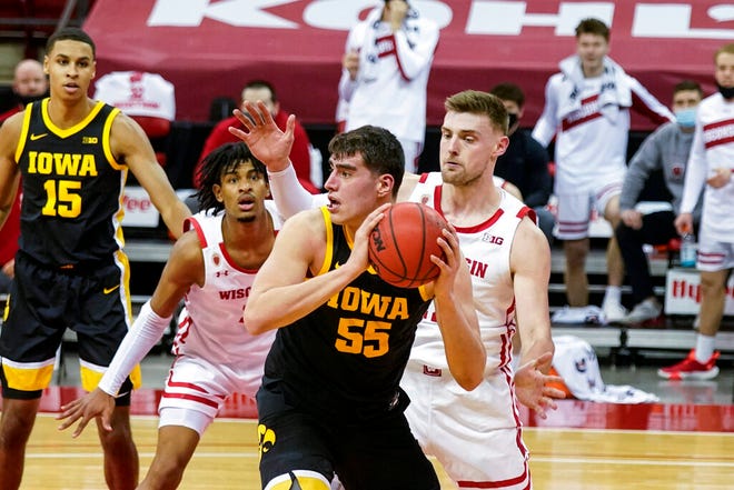 Iowa's Luka Garza (55) looks to pass as Wisconsin's Aleem Ford, left, and Micah Potter defend during the first half of an NCAA college basketball game Thursday, Feb. 18, 2021, in Madison, Wis. (AP Photo/Andy Manis)
