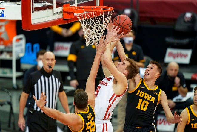 Iowa's Luka Garza (55) and Joe Wieskamp (10) defend against Wisconsin's Tyler Wahl (5) during the first half of an NCAA college basketball game Thursday, Feb. 18, 2021, in Madison, Wis. (AP Photo/Andy Manis)