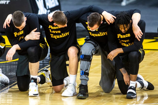Iowa players Connor McCaffery, Austin Ash, Jack Nunge and Ahron Ulis kneel prior to the national anthem before a NCAA Big Ten Conference men's basketball game against Wisconsin, Sunday, March 7, 2021, at Carver-Hawkeye Arena in Iowa City, Iowa.