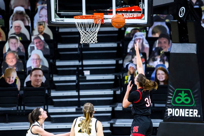 Nebraska forward Isabelle Bourne makes a basket as Iowa guard Caitlin Clark, left, and Iowa center Monika Czinano (25) defend during a NCAA Big Ten Conference women's basketball game, Saturday, March 6, 2021, at Carver-Hawkeye Arena in Iowa City, Iowa.