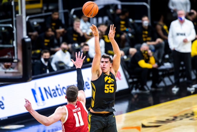 Iowa center Luka Garza (55) makes a 3-point basket as Wisconsin forward Micah Potter (11) defends during a NCAA Big Ten Conference men's basketball game, Sunday, March 7, 2021, at Carver-Hawkeye Arena in Iowa City, Iowa.