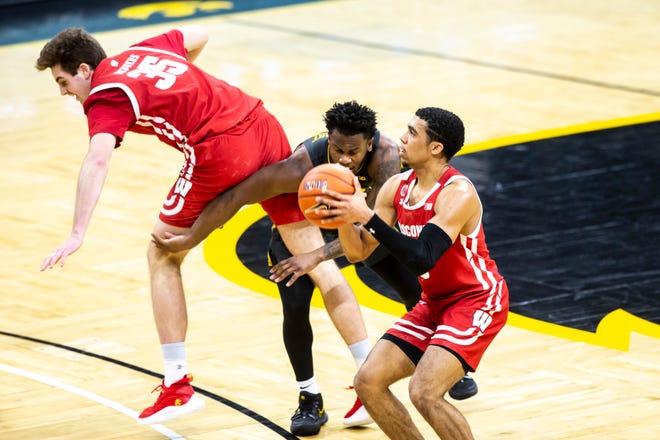 Wisconsin guard D'Mitrik Trice makes a 3-point basket as Iowa guard Joe Toussaint, middle, gets caught up on Wisconsin forward Nate Reuvers (35) during a NCAA Big Ten Conference men's basketball game, Sunday, March 7, 2021, at Carver-Hawkeye Arena in Iowa City, Iowa.