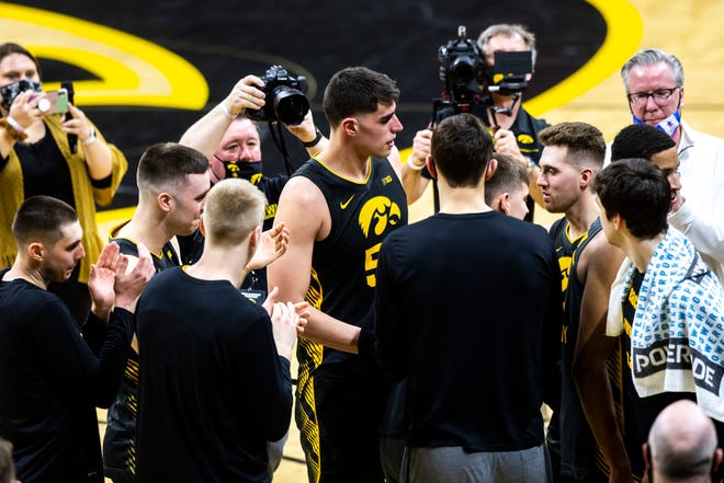Iowa center Luka Garza (55) and Iowa guard Jordan Bohannon (3) are embraced by teammates after a NCAA Big Ten Conference men's basketball game against Wisconsin, Sunday, March 7, 2021, at Carver-Hawkeye Arena in Iowa City, Iowa.