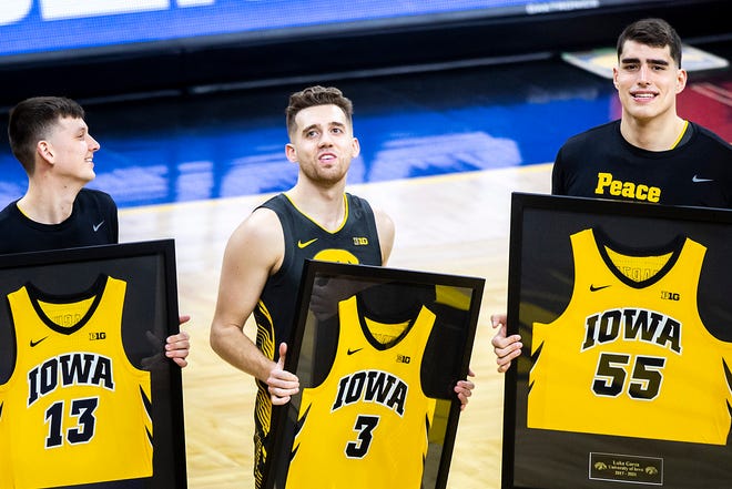 Iowa Hawkeyes seniors, from left, Iowa guard Austin Ash (13) Iowa guard Jordan Bohannon (3) and Iowa center Luka Garza (55) hold framed jerseys during a senior day presentation before a NCAA Big Ten Conference men's basketball game against Wisconsin, Sunday, March 7, 2021, at Carver-Hawkeye Arena in Iowa City, Iowa.
