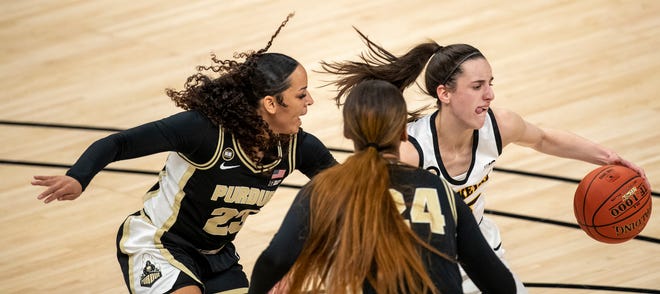 Iowa Hawkeyes guard Caitlin Clark (22) controls a possession as she is defended by Purdue Boilermakers guard Kayana Traylor (23) and center Ra Shaya Kyle (24) on Wednesday, March 10, 2021, during the women's Big Ten basketball tournament from Bankers Life Fieldhouse in Indianapolis.