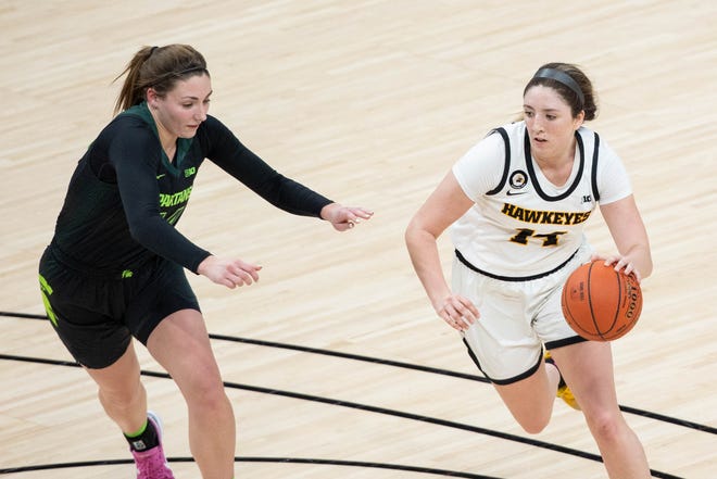 Mar 12, 2021; Indianapolis, IN, USA; Iowa Hawkeyes guard McKenna Warnock (14) dribbles the ball while Michigan State Spartans forward Kendall Bostic (44) defends  in the third quarter at Bankers Life Fieldhouse. Mandatory Credit: Trevor Ruszkowski-USA TODAY Sports