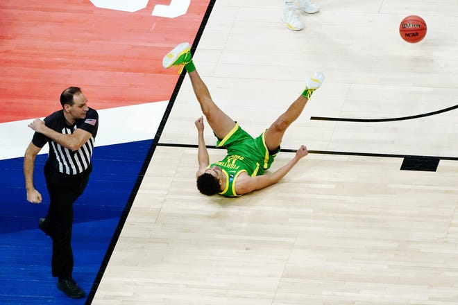 Referee Bo Boroski, left, gestures as Oregon Ducks guard Will Richardson (0) falls after being fouled by the Iowa Hawkeyes during the first half in the second round of the 2021 NCAA Tournament Monday, March 22, 2021, at Bankers Life Fieldhouse.