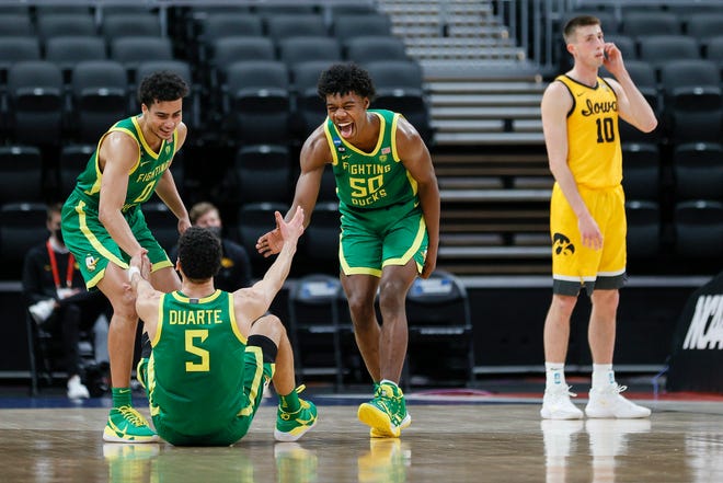 Oregon Ducks players Will Richardson (0) and Eric Williams Jr. (50) react with Chris Duarte (5) after Duarte was fouled by the Iowa Hawkeyes as Iowa's Joe Wieskamp, right, looks on in the second round game of the 2021 NCAA Men's Basketball Tournament at Bankers Life Fieldhouse on March 22, 2021 in Indianapolis, Indiana.
