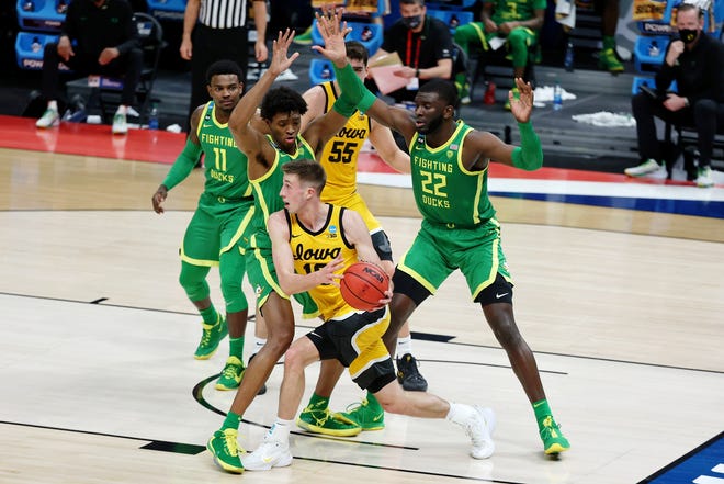 Iowa's Joe Wieskamp, middle, looks to pass while defended by Oregon Ducks forward Chandler Lawson, left, and center Franck Kepnang (22) during the first half in the second round of the 2021 NCAA Tournament, March 22, 2021, at Bankers Life Fieldhouse.