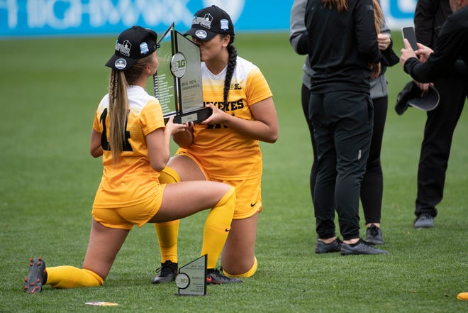 From left, Iowa forward Meike Ingles (14) and Aleisha Ganief (10) kiss the Big Ten women's soccer tournament trophy after an NCAA college soccer game in the final of the Big Ten Conference tournament, Sunday, April 17, 2021, in State College, Pennsylvania. Iowa defeated Wisconsin 1-0 in the tournament final.