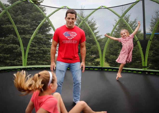 Four-time Iowa high school wrestling champion T.J. Sebolt jumps on the trampoline with his daughters Mila, 7, left, and Nova, 4, in the back yard of their home in Jefferson on Tuesday, July 13, 2021.