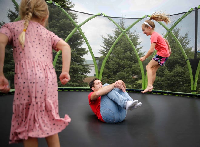Four-time Iowa high school wrestling champion T.J. Sebolt jumps on the trampoline with his daughters Mila, 7, right, and Nova, 4, in the back yard of their home in Jefferson on Tuesday, July 13, 2021.