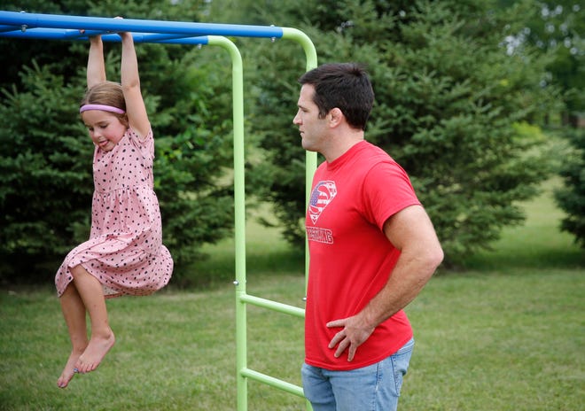 Four-time Iowa high school wrestling champion T.J. Sebolt watches as his daughter, Nova, 4, makes her way across the bars on a piece of playground equipment in the back yard of their home in Jefferson on Tuesday, July 13, 2021.