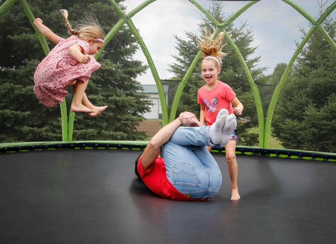 Four-time Iowa high school wrestling champion T.J. Sebolt jumps on the trampoline with his daughters Mila, 7, right, and Nova, 4, in the back yard of their home in Jefferson on Tuesday, July 13, 2021.