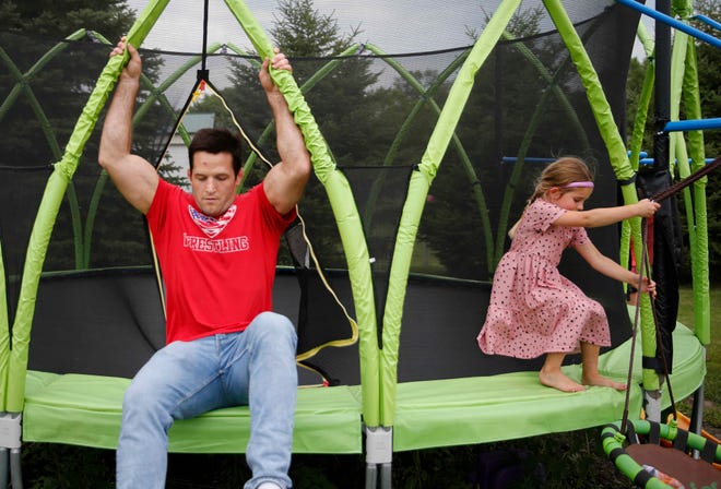 Four-time Iowa high school wrestling champion T.J. Sebolt exits the trampoline as his daughter Nova, 4, makes her way to a swing as they play in the back yard of their home in Jefferson on Tuesday, July 13, 2021.