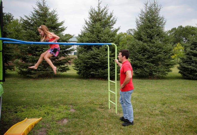Four-time Iowa high school wrestling champion T.J. Sebolt watches as his daughter, Mila, 7, makes her way across the bars on a piece of playground equipment in the back yard of their home in Jefferson on Tuesday, July 13, 2021.