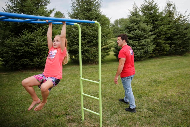 Four-time Iowa high school wrestling champion T.J. Sebolt watches as his daughter, Mila, 7, makes her way across the bars on a piece of playground equipment in the back yard of their home in Jefferson on Tuesday, July 13, 2021.