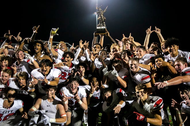 Iowa City High Little Hawk players celebrate with the Titans Trophy after a varsity high school football game in the Battle for Zeus against Iowa City Liberty, Friday, Aug. 27, 2021, at Liberty High School in North Liberty, Iowa.