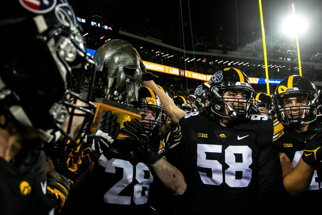 Iowa Hawkeyes players celebrate with the Floyd of Rosedale trophy after a NCAA Big Ten Conference football game against Minnesota, Saturday, Nov. 13, 2021, at Kinnick Stadium in Iowa City, Iowa. The Hawkeyes beat the Golden Gophers, 27-22.
