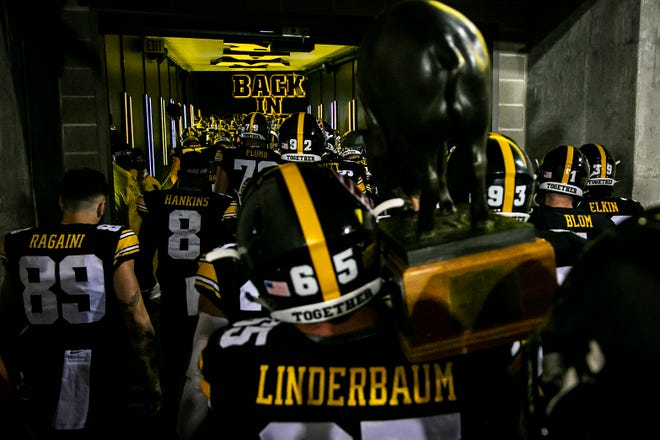 Iowa center Tyler Linderbaum (65) carries the Floyd of Rosedale trophy into the locker room with teammates after a NCAA Big Ten Conference football game against Minnesota, Saturday, Nov. 13, 2021, at Kinnick Stadium in Iowa City, Iowa. The Hawkeyes beat the Golden Gophers, 27-22.