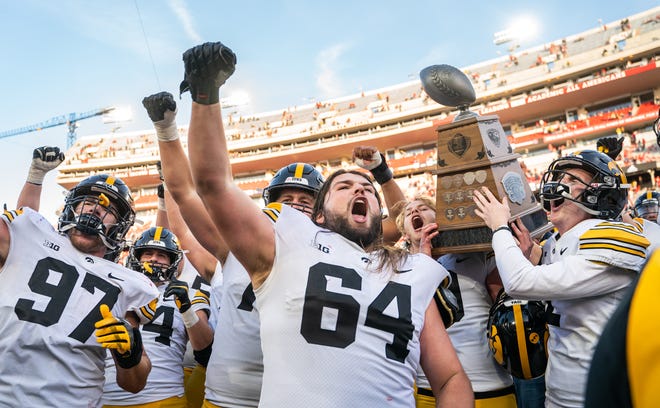 Iowa Hawkeyes players Tory Taylor, second from right, and Ryan Gersonde hoist the Heroes Trophy as defensive lineman Zach VanValkenburg (97) and offensive lineman Kyler Schott (64) cheer following their win over the Nebraska Cornhuskers, Friday, Nov. 26, 2021, at Memorial Stadium, in Lincoln, Neb.