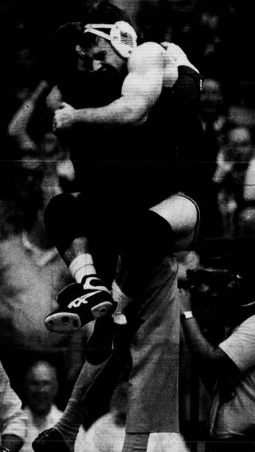 Iowa wrestler Mark Reiland leaps into the arms of assistant coach Jim Zalesky after pinning his opponent in the 167-pound championship match in 1991.