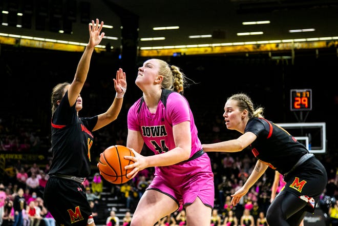 Iowa's Addison O'Grady (44) drives to the basket as Maryland guards Katie Benzan, left, and Taisiya Kozlova defend during a NCAA Big Ten Conference women's basketball game, Monday, Feb. 14, 2022, at Carver-Hawkeye Arena in Iowa City, Iowa.