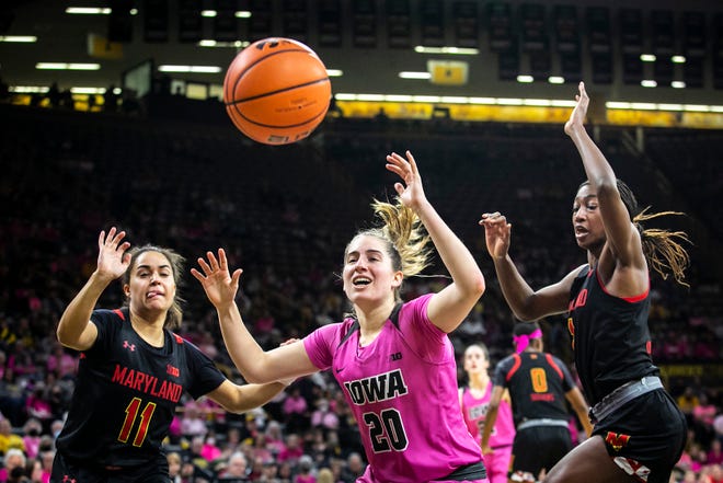 Iowa guard Kate Martin (20) reacts as a ball soars out of bounds as Maryland guards Katie Benzan (11) and Diamond Miller, right, defend during a NCAA Big Ten Conference women's basketball game, Monday, Feb. 14, 2022, at Carver-Hawkeye Arena in Iowa City, Iowa.