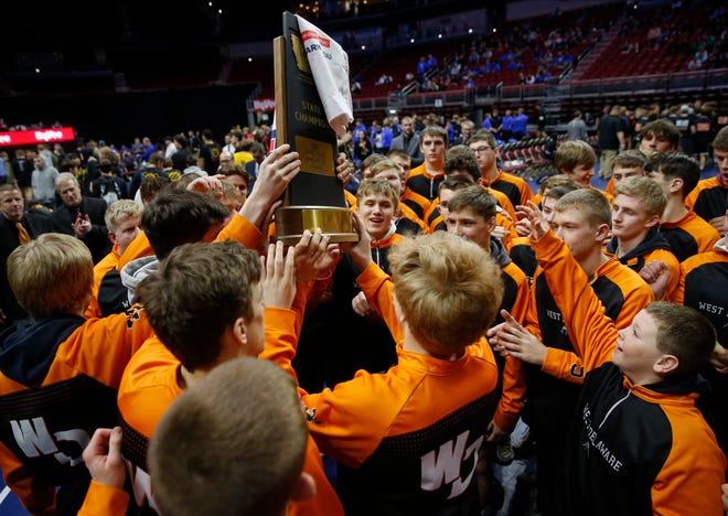 Members of the West Delaware wrestling team celebrate a Class 2A state wrestling dual championship win over Independence at Wells Fargo Arena in Des Moines on Wednesday, Feb. 16, 2022.
