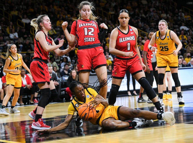 Iowa's guard Tomi Taiwo (1) falls against Illinois State's guard Maya Wong (12) and forward Jasmine McGinnis-Taylor (1) during the opening round of the Women's NCAA Basketball Tournament at Carver-Hawkeye Arena Friday, March 18, 2022, in Iowa City.