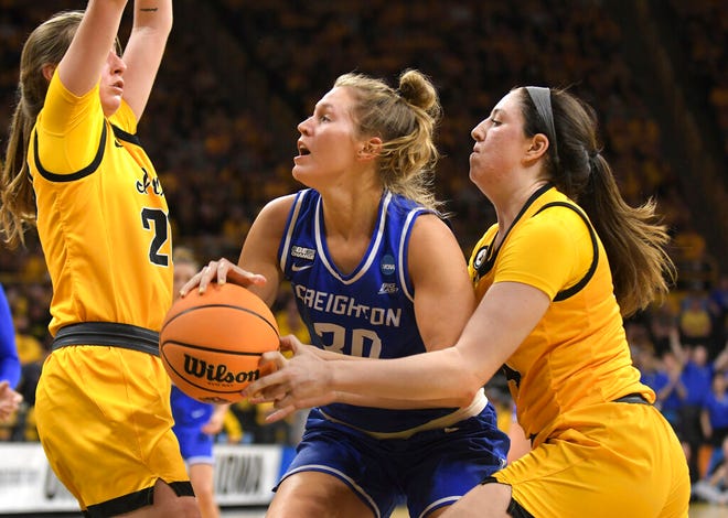 Creighton guard Morgan Maly (30) drives to the basket as Iowa guard McKenna Warnock (14) reaches for the ball during the first half of a second-round game in the NCAA women's college basketball tournament, Sunday, March 20, 2022, in Iowa City, Iowa. (AP Photo/Ron Johnson)