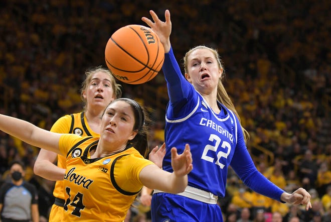 Creighton guard Carly Bachelor (22) and Iowa guard McKenna Warnock (14) battle for a loose ball during the first half of a second-round game in the NCAA women's college basketball tournament, Sunday, March 20, 2022, in Iowa City, Iowa. (AP Photo/Ron Johnson)