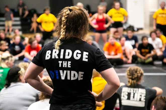 A wrestler wears a shirt reading "Bridge the D1vide" during a girls wrestling technique camp, Wednesday, July 6, 2022, at the GreenState Family Fieldhouse in Coralville, Iowa.