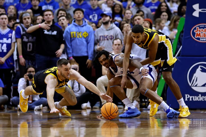 Iowa guard Connor McCaffery, left, dives for a loose ball in front of Seton Hall guard Dre Davis, second from right, and Iowa forward Kirs Murray during the first half of an NCAA college basketball game, Wednesday, Nov. 16, 2022, at the Prudential Center in Newark, N.J.