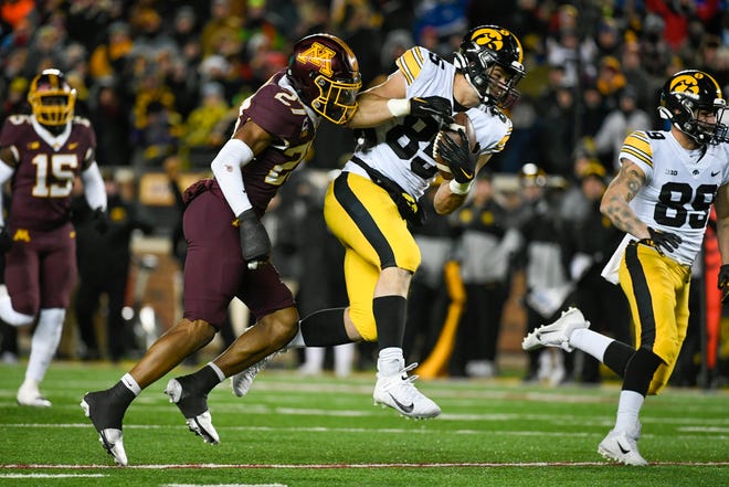 Iowa tight end Luke Lachey (85) catches a pass as he is tackled by Minnesota defensive back Tyler Nubin (27) during the second half an NCAA college football game, Saturday, Nov. 19, 2022, at Huntington Bank Stadium in Minneapolis, Minn.