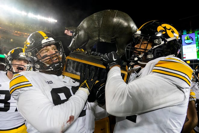 Iowa's John Waggoner, left, and Yahya Black celebrate with the Floyd of Rosedale trophy after the game against the Minnesota Golden Gophers, Saturday, Nov. 19, 2022, at Huntington Bank Stadium in Minneapolis, Minn. The Hawkeyes defeated the Golden Gophers 13-10.