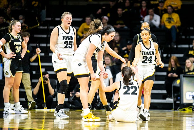 Iowa guard Caitlin Clark (22) gets helped up by teammates Monika Czinano (25) McKenna Warnock and Gabbie Marshall (24) during a NCAA Big Ten Conference women's basketball game against Purdue, Thursday, Dec. 29, 2022, at Carver-Hawkeye Arena in Iowa City, Iowa.